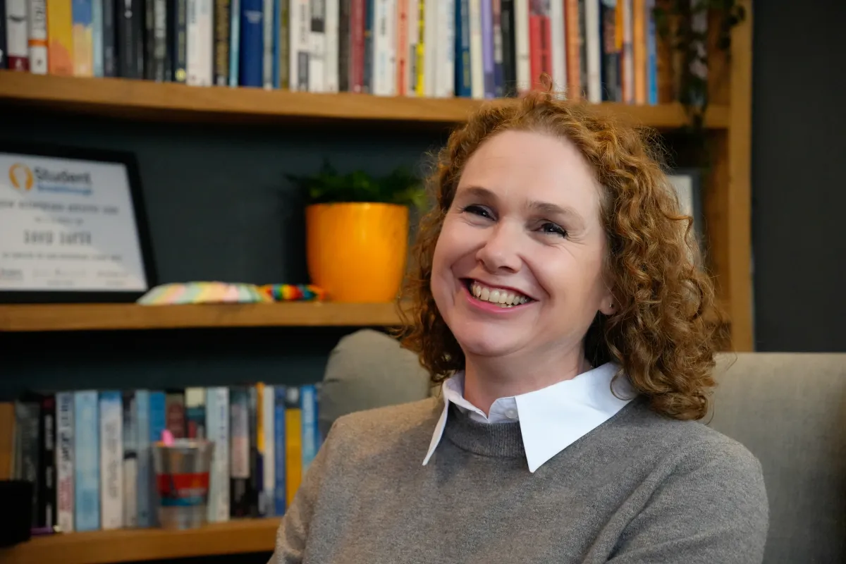 Kirsty Goddard laughing warmly in front of a bookshelf